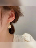 Par de aretes de aro con circonias y bola de perlas sobre fondo gris