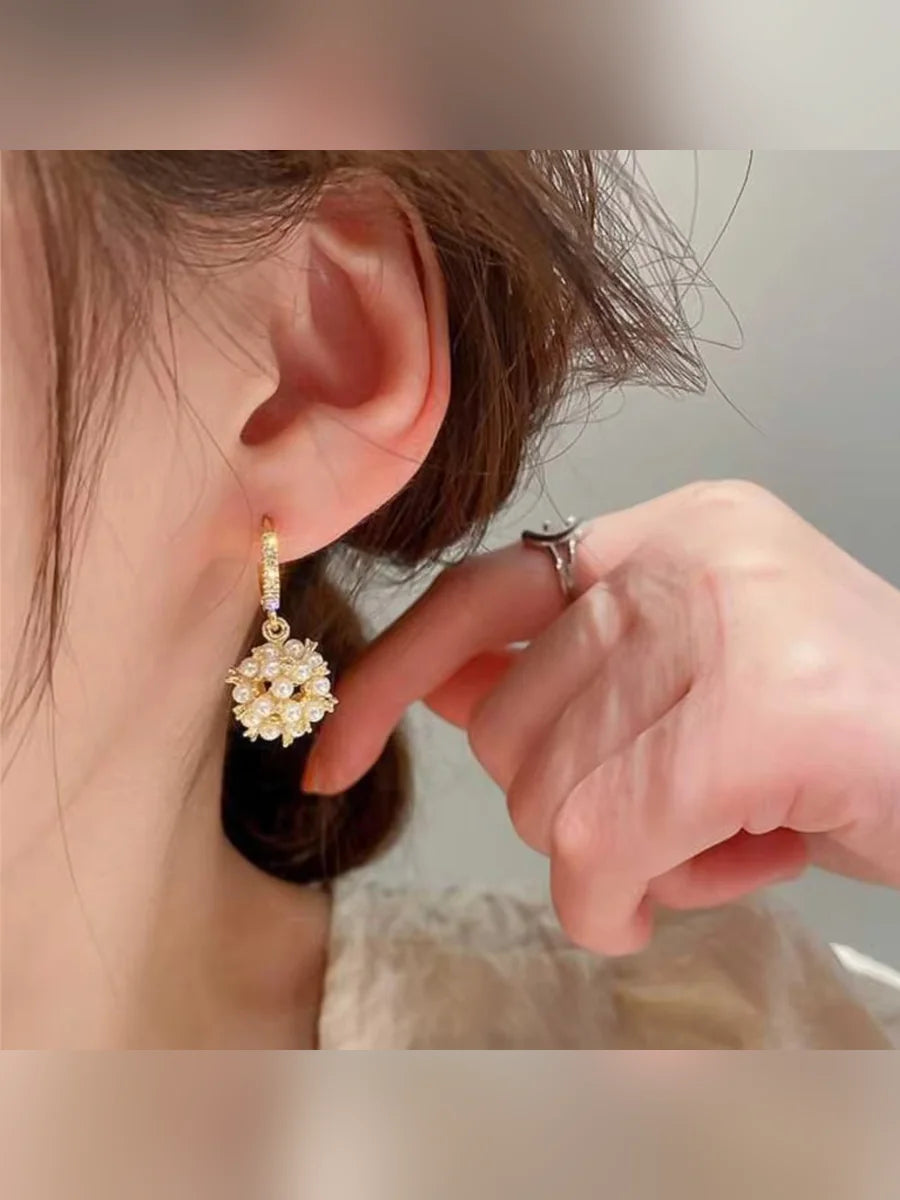 Primer plano de un arete de aro con bola de perlas en la oreja