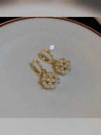 Aretes dorados con bola de perlas sobre un plato