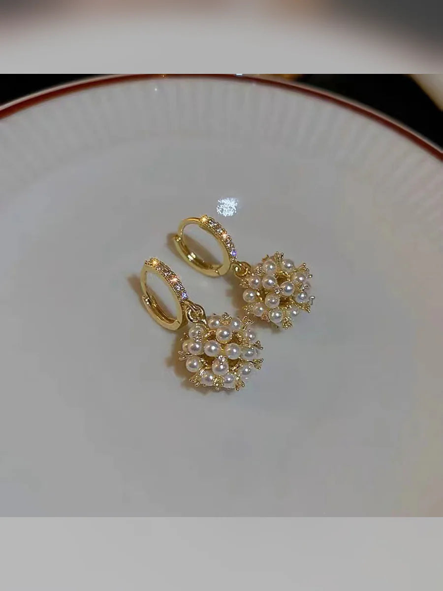 Aretes dorados con bola de perlas sobre un plato