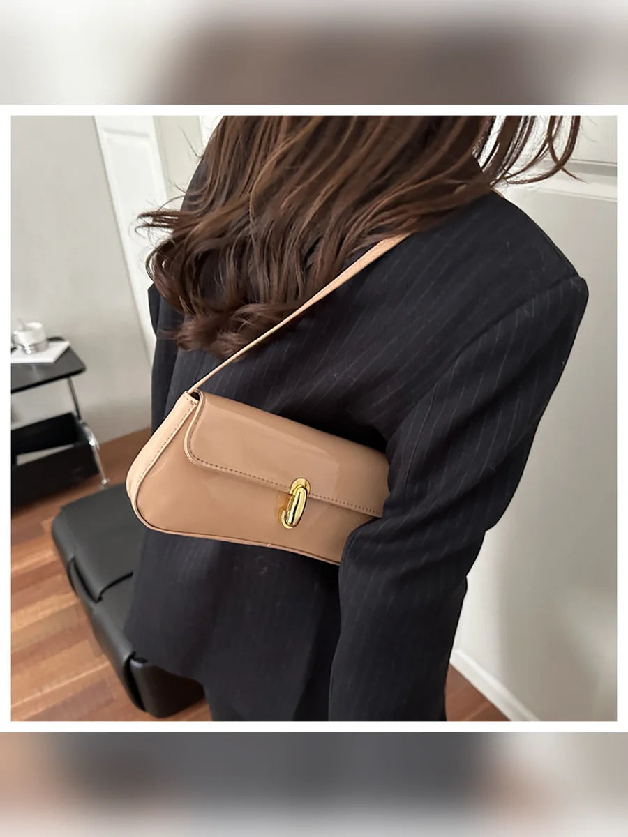 Mujer con blazer oscuro llevando el bolso de hombro caqui al hombro