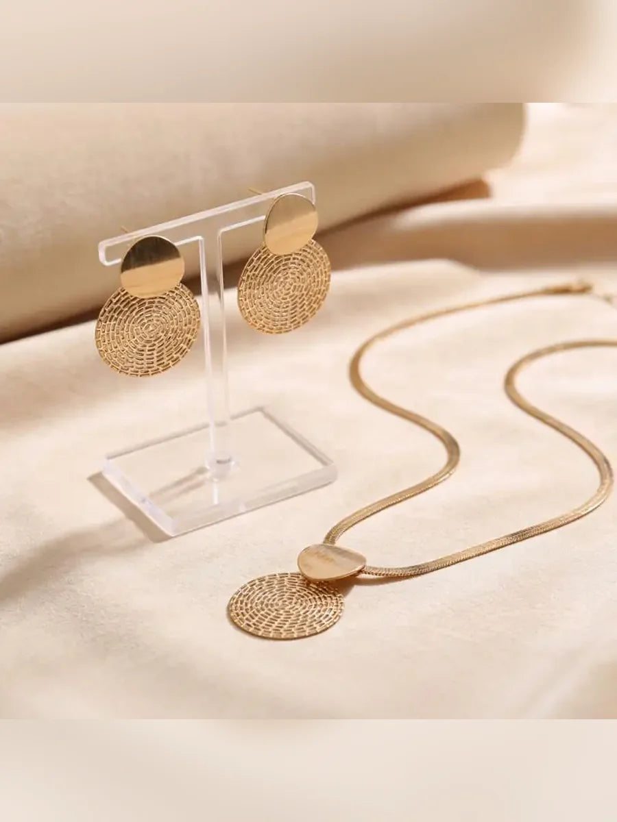 Aretes de disco dorado en expositor transparente junto al collar de cadena plana