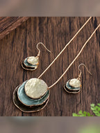 Collar y aretes con dijes circulares esmaltados en tonos verde azulado sobre madera