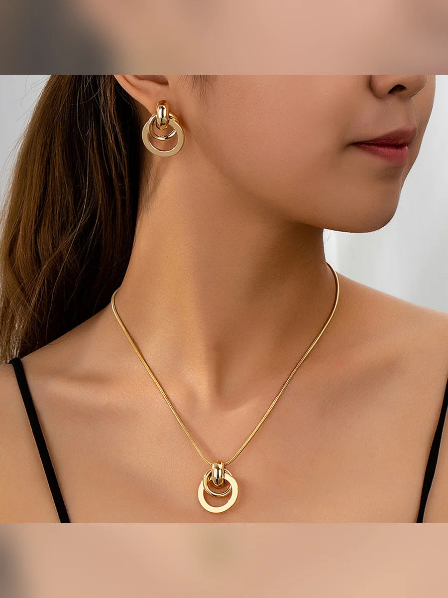 Mujer con collar dorado de dije circular y aretes de aros entrelazados