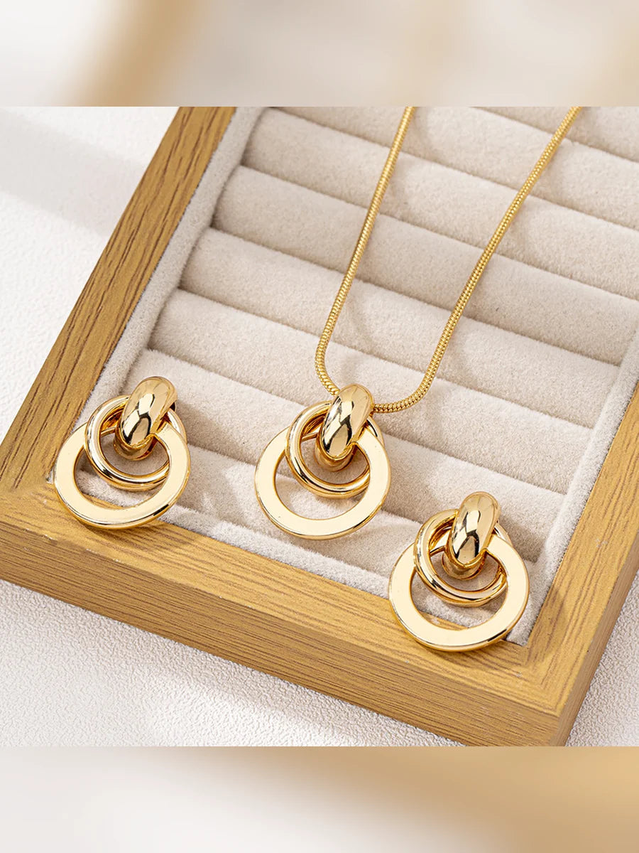 Set de collar y aretes dorados de aros entrelazados en un expositor de madera