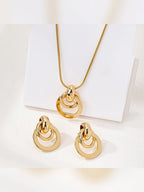 Dije y aretes dorados de aros entrelazados sobre soporte blanco