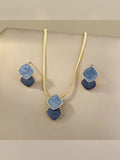 Set de collar y aretes con rombos esmaltados en azul sobre fondo beige