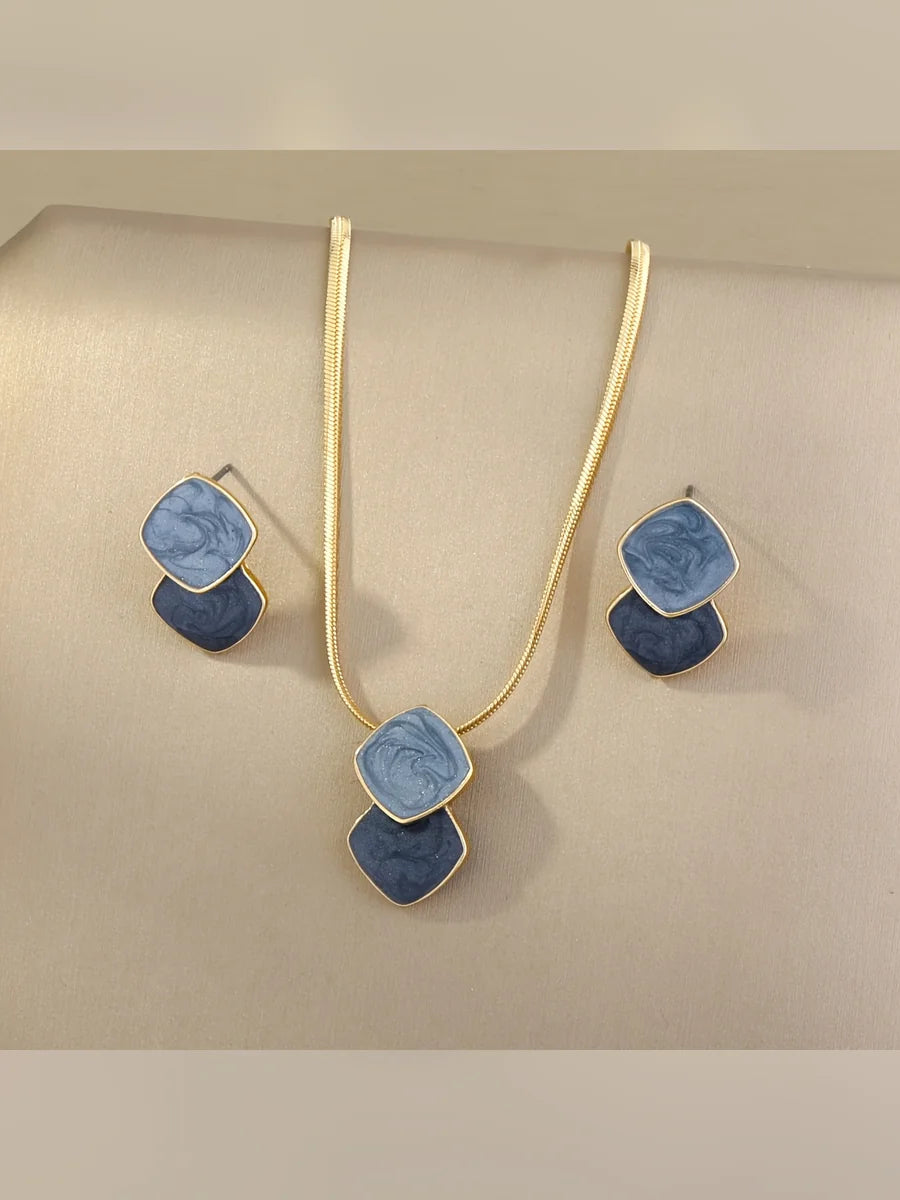 Set de collar y aretes con rombos esmaltados en azul sobre fondo beige