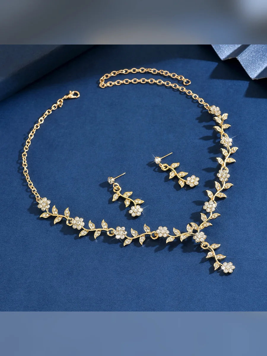 Set dorado de collar en Y y aretes de hojas con cristales sobre fondo azul