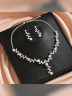 Collar y aretes plateados de hojas y flores en una caja de presentación negra
