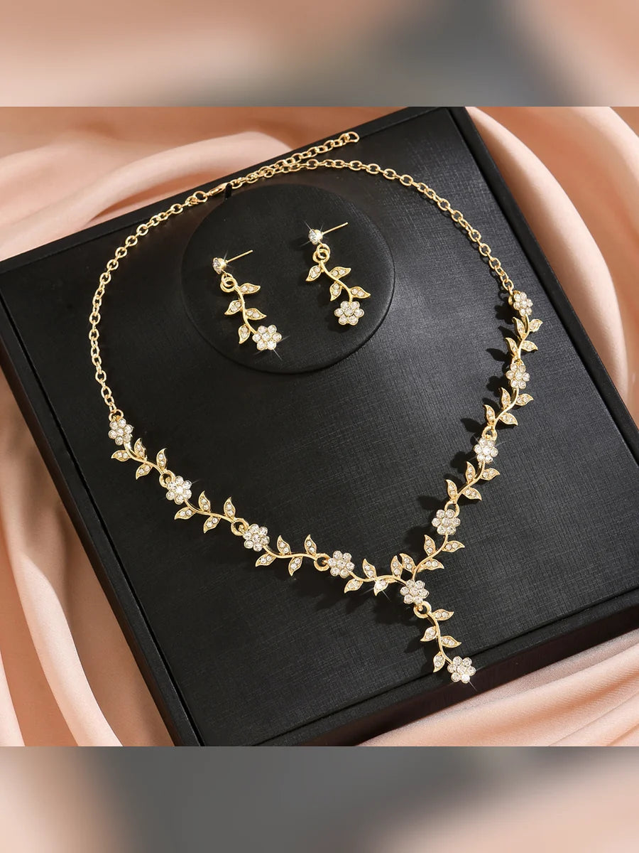 Collar y aretes dorados de hojas y flores en una caja de presentación negra