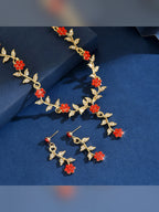 Detalle del collar dorado con flores rojas y aretes colgantes
