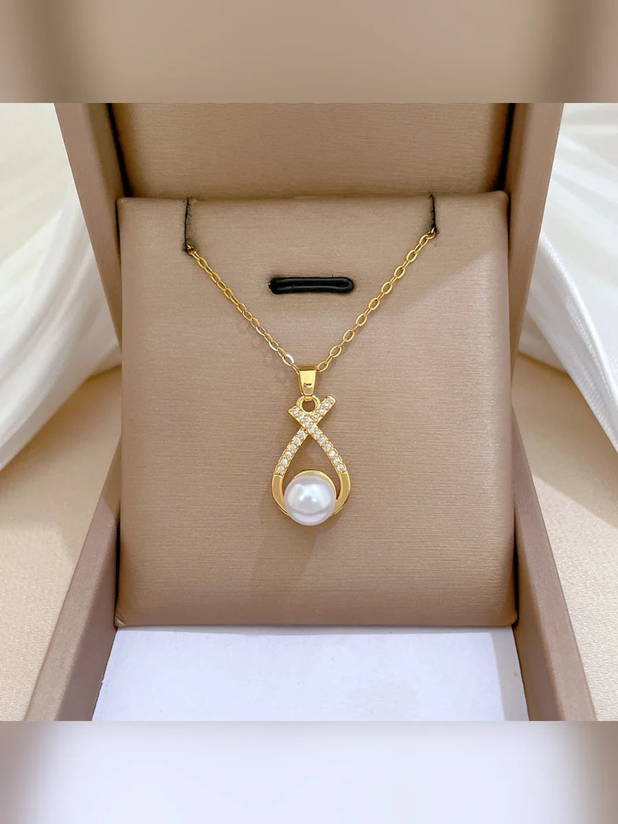 Collar dorado con dije de perla y cristales en una caja