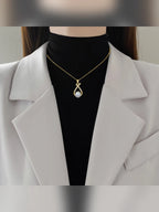 Mujer con blazer claro luciendo el collar dorado con dije de perla