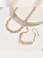 Set de collar y pulsera trenzados en oro rosa sobre fondo claro