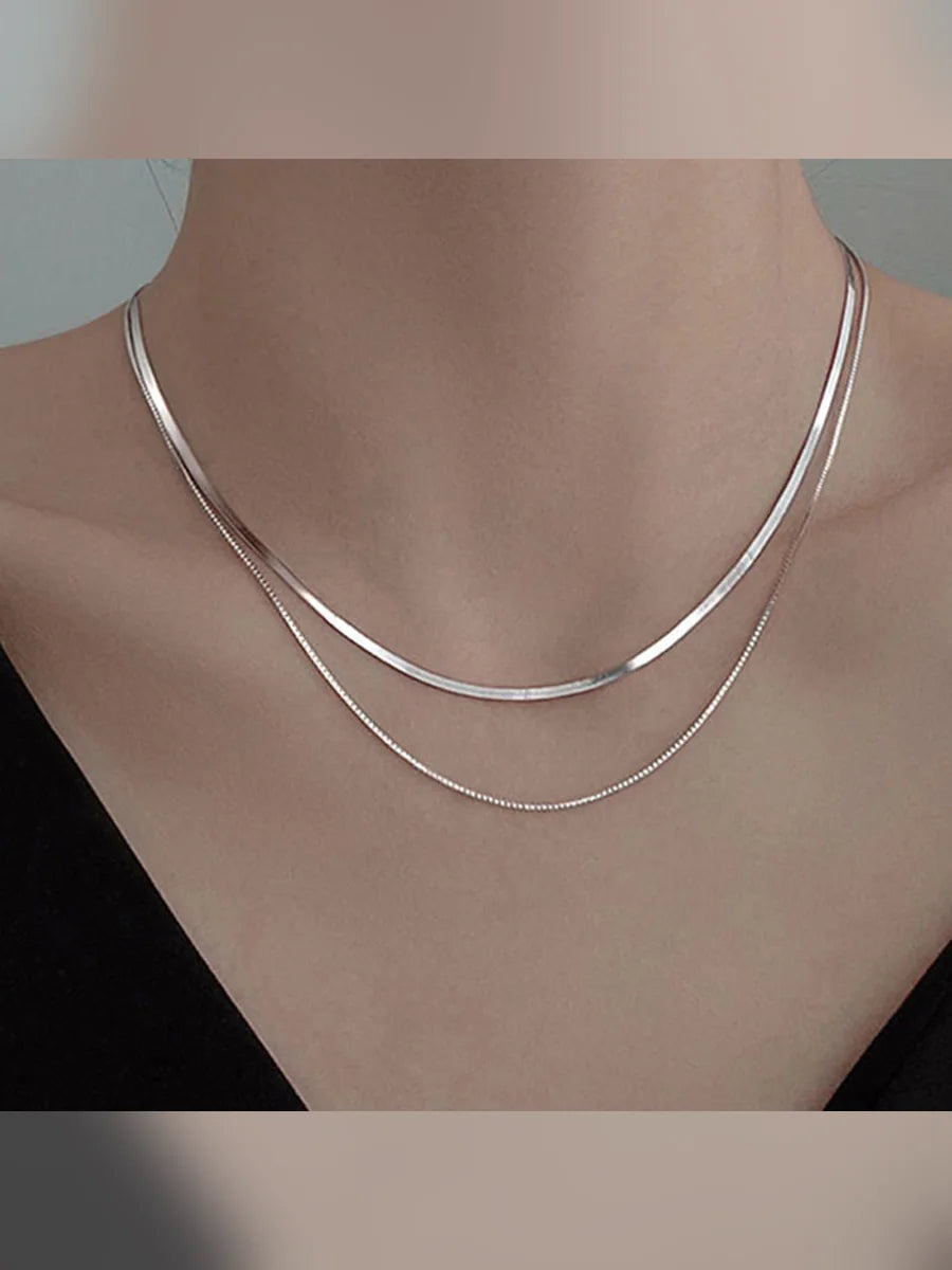 Mujer con collar plateado de doble capa sobre la clavícula