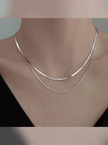 Mujer con collar plateado de doble capa sobre la clavícula