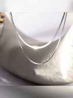 Detalle del collar de plata con cadena plana y cadena fina en caja