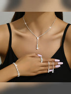 Mujer con set de collar en Y, aretes, pulsera y anillo de cristales plateados