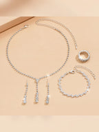 Collar, aretes colgantes, pulsera y anillo de cristales plateados dispuestos juntos