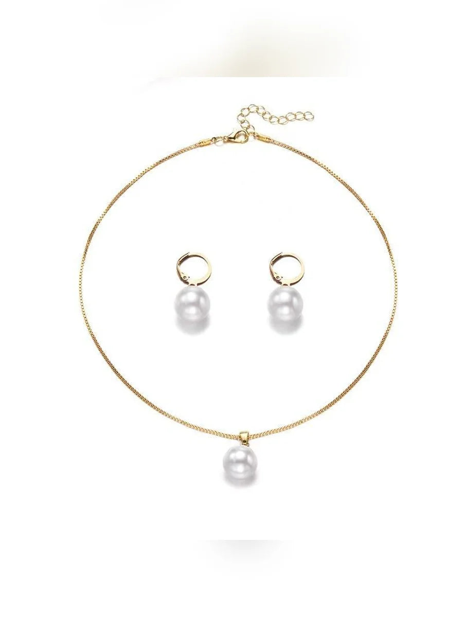 Collar dorado con dije de perla y aretes de aro con perla sobre fondo blanco