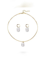 Collar dorado con dije de perla y aretes de aro con perla sobre fondo blanco