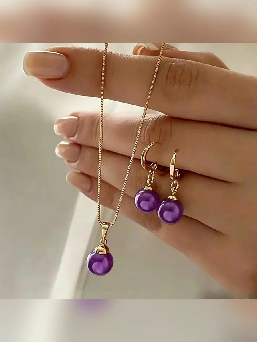Mano sosteniendo el set de collar y aretes con perlas moradas