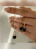 Mano sosteniendo el set de collar y aretes con perlas negras