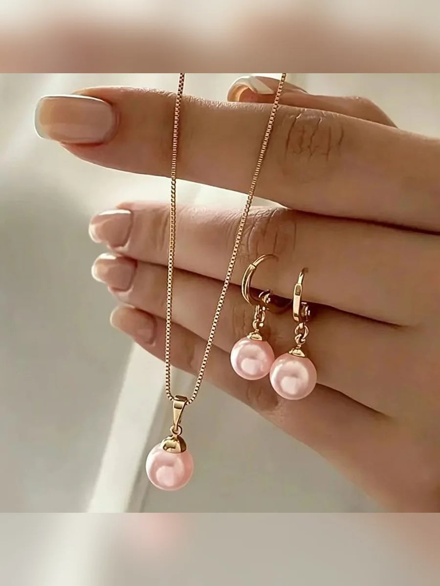 Mano sosteniendo el set de collar y aretes con perlas rosas