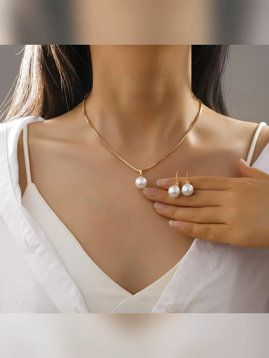 Mujer con camisa blanca luciendo el collar dorado con perla y aretes pequeños de perla
