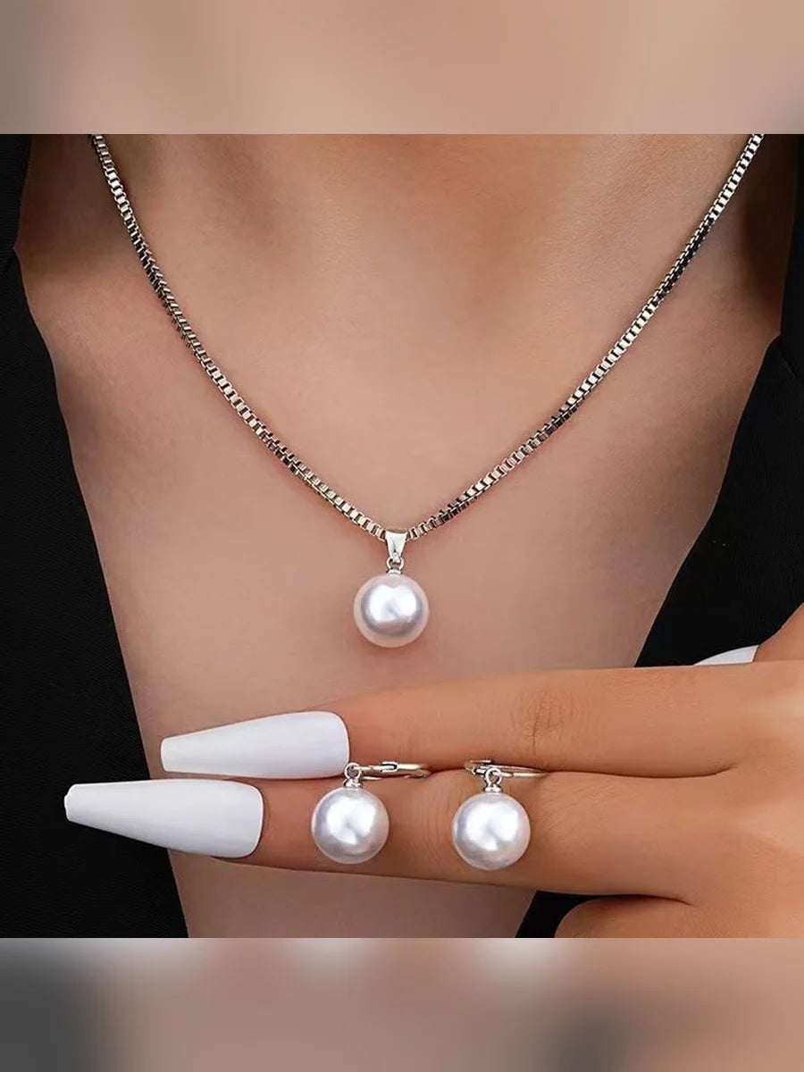 Mujer luciendo el collar plateado con dije de perla y aretes de perla