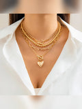 Collar multicapa dorado con dije de corazón sobre camisa blanca
