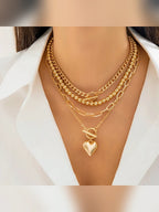 Mujer con collar multicapa dorado de cadenas y bolitas con dije de corazón