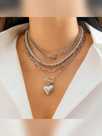 Collar multicapa plateado con dije de corazón sobre camisa blanca