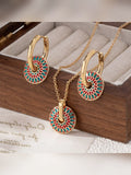 Set de collar y aretes de aro con disco de colores verde y rojo sobre caja de joyería
