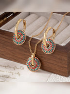 Set de collar y aretes de aro con disco de colores verde y rojo sobre caja de joyería