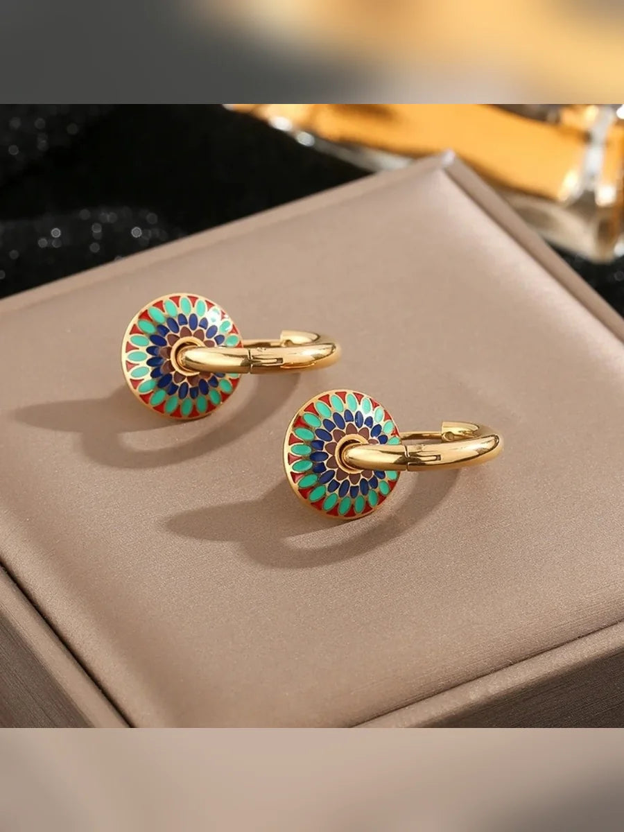 Aretes de aro con disco de colores sobre superficie beige