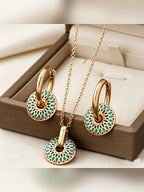 Collar dorado con dije de disco de colores y aretes a juego en una caja