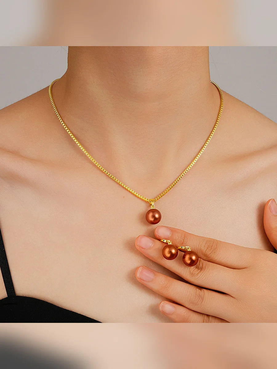 Mujer con collar dorado de perla marrón y aretes a juego