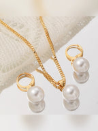 Aretes de aro con perla y collar de cadena dorada sobre tejido blanco