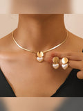 Mujer con collar dorado y aretes con disco y corazón nacarado