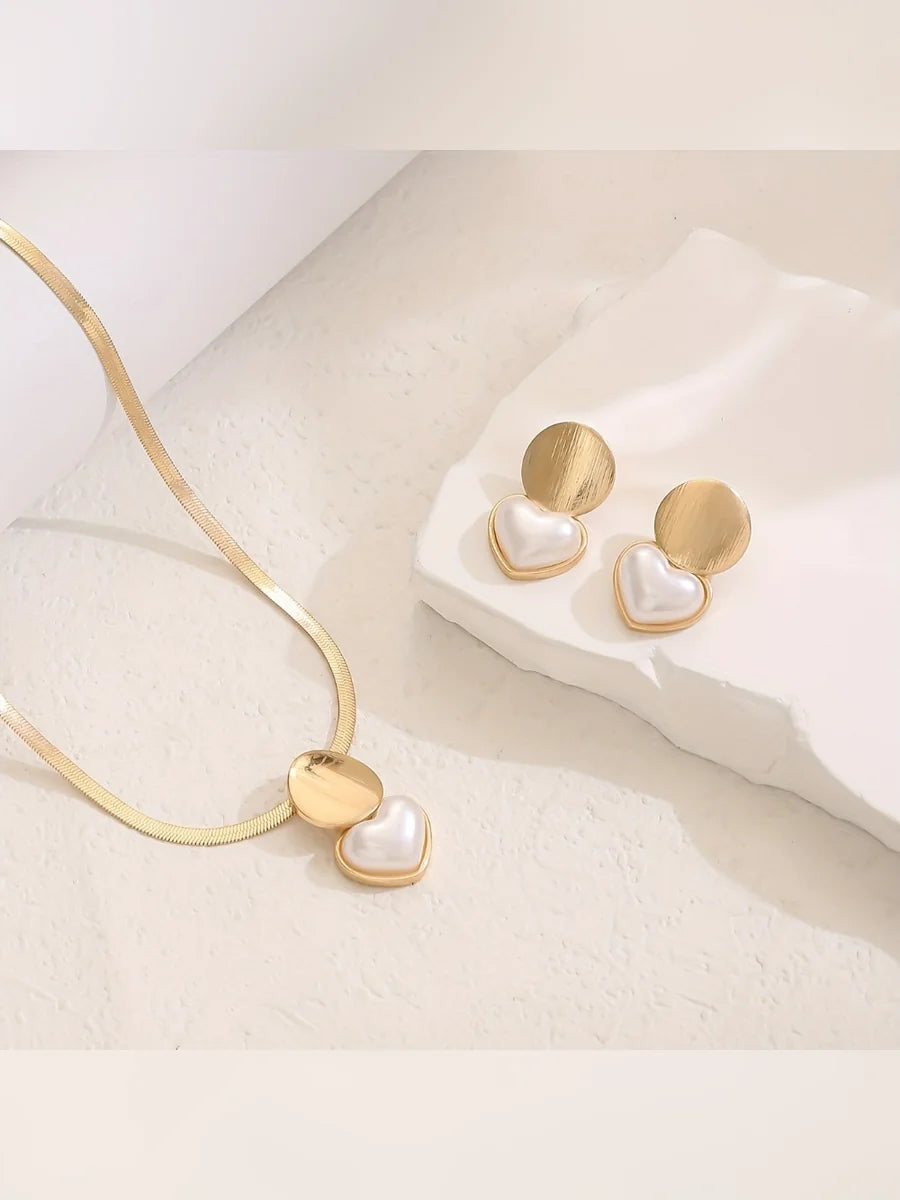 Aretes dorados con corazón nacarado junto al collar de cadena plana